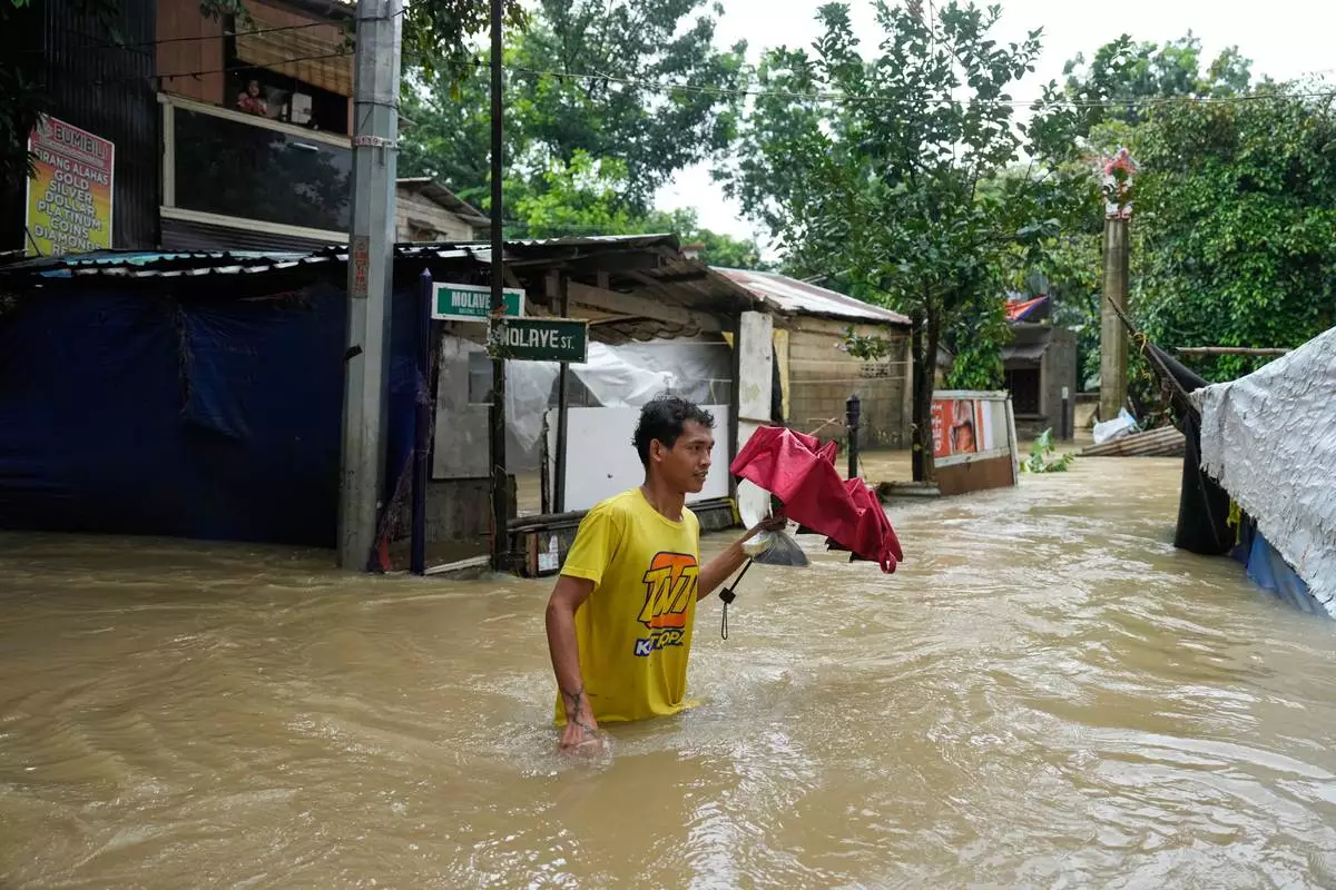 A man walks through floodwaters caused by heavy seasonal monsoon rains at Bagong Silangan village in Quezon city, Metro Manila, Philippines Monday, Aug. 10, 2026. (AP Photo/Aaron Favila) CORRECTION: Corrects typo in location to Silangan, instead of Silagan
