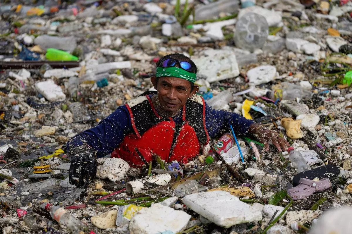 A worker tries to clear a sea of garbage and debris brought by intense monsoon rains at the Redemptorist Water Channel in Paranaque city, Metro Manila, Philippines Tuesday, Aug. 11, 2026. (AP Photo/Aaron Favila)