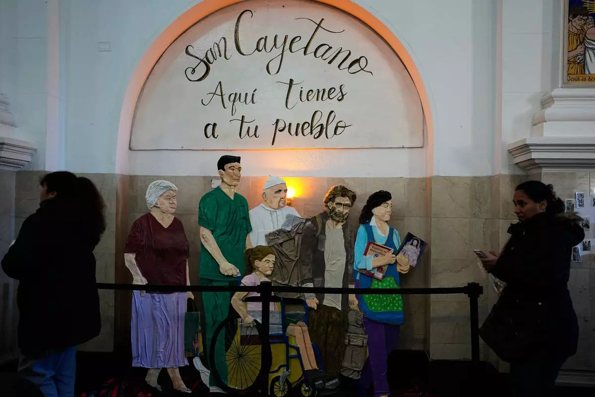 An art installation with a message that reads in Spanish: "Here are your people" and that includes a depiction of Pope Leo XIV is on display inside the Church of San Cayetano during the annual pilgrimage honoring Saint Cajetan, the patron saint of work, in Buenos Aires, Argentina, Friday, Aug. 7, 2026. (AP Photo/Natacha Pisarenko)