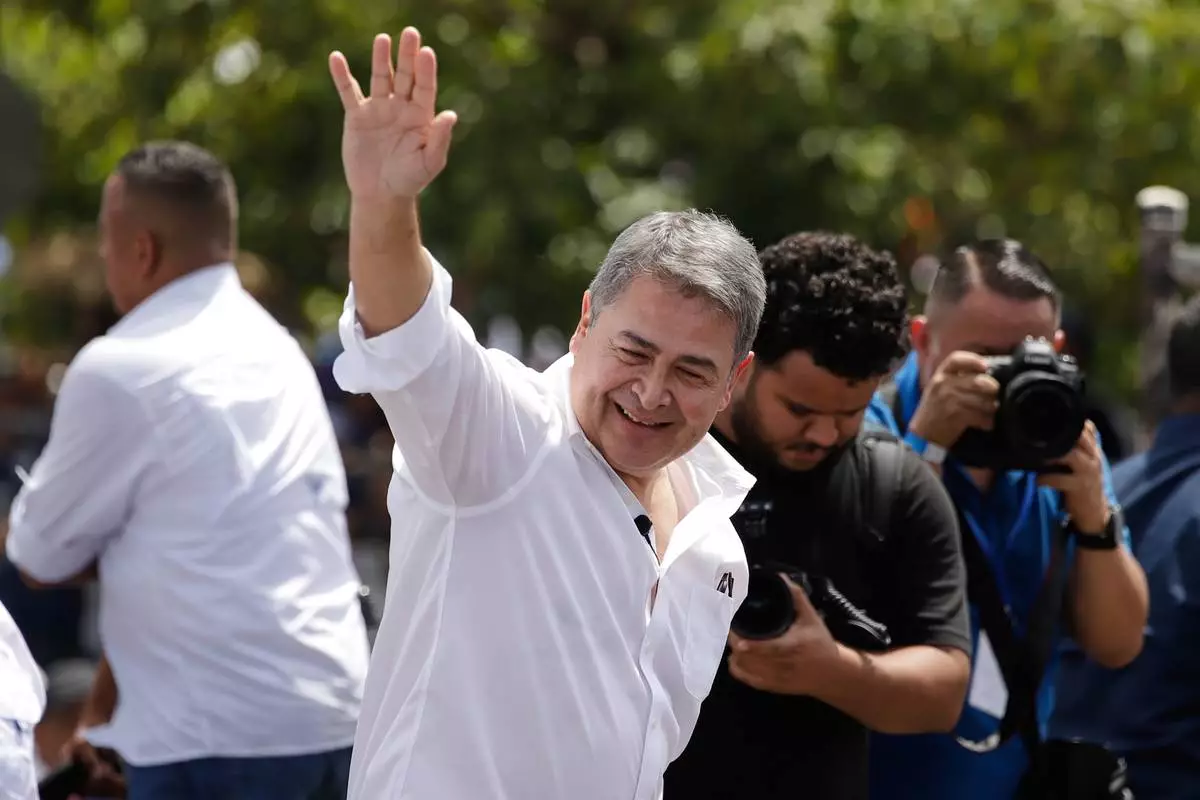 Former Honduran President Juan Orlando Hernández waves after his arrival to Toncontin airport in Tagucigalpa, Honduras, Sunday, July 26, 2026. (AP Photo/Fernando Destephen)