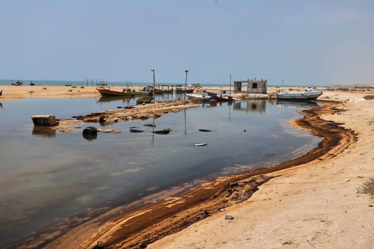 Oil residue lines the shore near fishing boats on Qeshm Island, Iran, Thursday, Aug. 13, 2026, amid ongoing wartime attacks on vessels and infrastructure in and around the Strait of Hormuz, though the spill's source has not been independently determined.(Amirhosein Khorgooi/ISNA via AP)