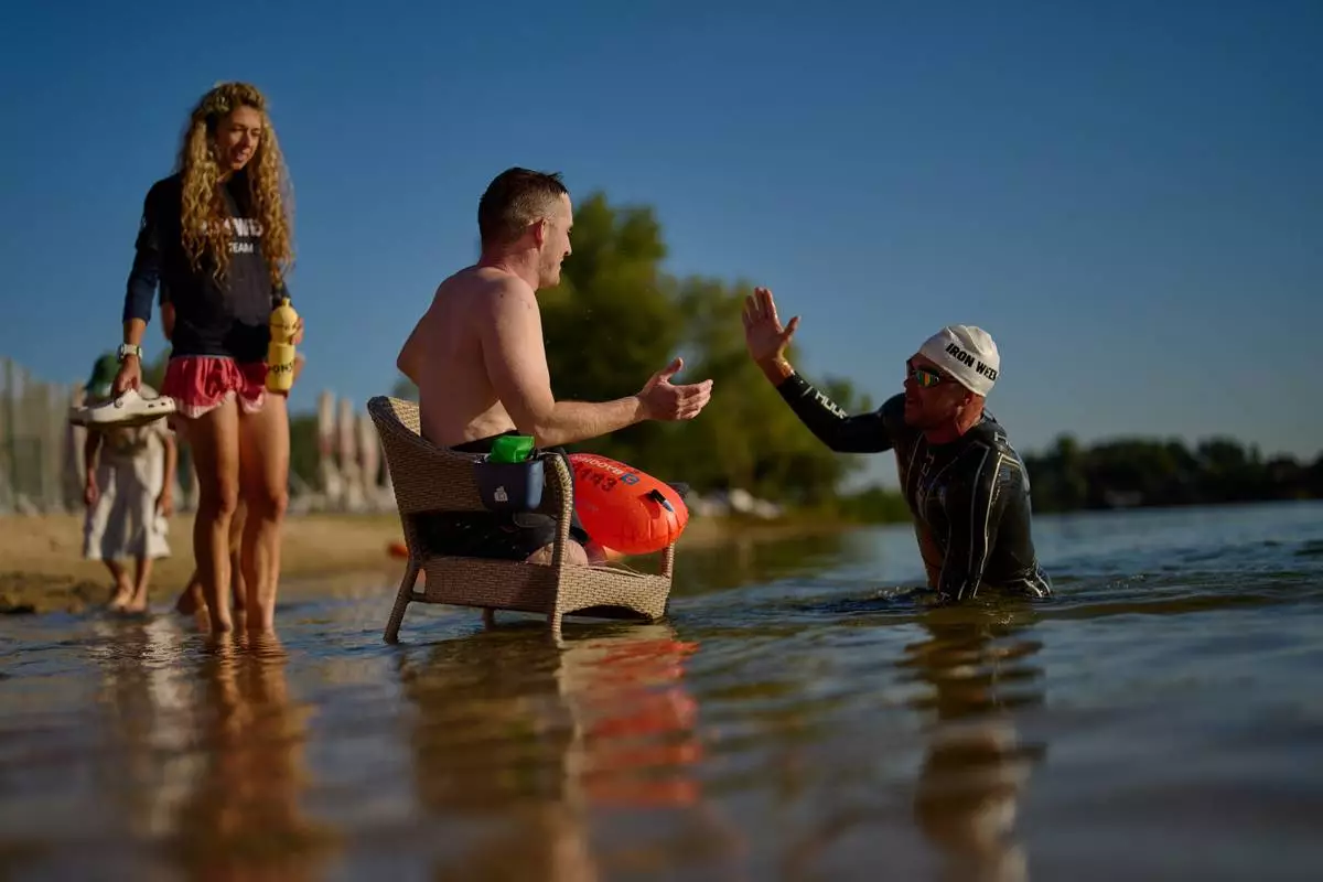 Ukrainian war veteran Maksym Yuzviak, center, is greet by sports celebrity Danylo Sapunov during an athletic event to encourage people and injured soldiers to take part in sports at a lake on the outskirts of Kyiv, Monday, Aug. 24, 2026, during the 35th anniversary of Ukraine's Independence Day. (AP Photo/Francisco Seco) Corrects spelling of Maksym Yuzviak, not Maxim Yuzvyak