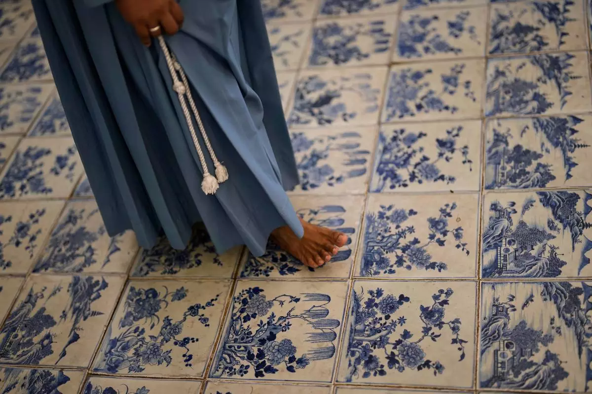A nun walks through the main hall with its blue-and-white Chinese porcelain tile floor at the 458-year-old Paradesi Synagogue in the historic Jew Town neighborhood of Kochi, India, Wednesday, May 20, 2026. (AP Photo/Aijaz Rahi)