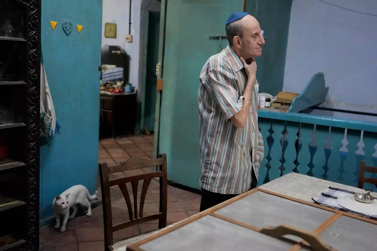 Keith Hallegua, a Paradesi Jew, stands next to his dining table as his cat walks past at his home in the historic Jew Town neighborhood of Kochi, India, Thursday, May 21, 2026. (AP Photo/Aijaz Rahi)