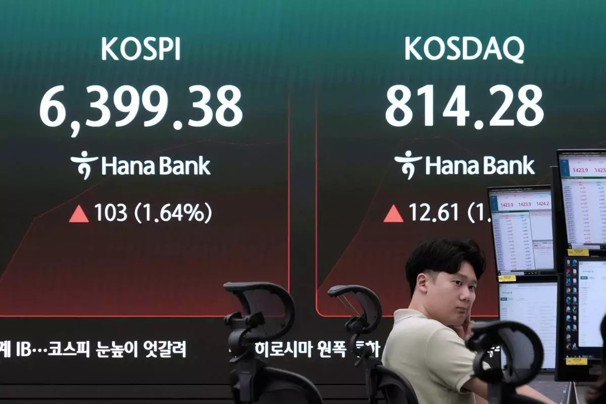 A currency trader watches monitors near a screen showing the Korea Composite Stock Price Index (KOSPI) at the foreign exchange dealing room of the Hana Bank headquarters in Seoul, South Korea, Friday, Aug. 7, 2026. (AP Photo/Ahn Young-joon)
