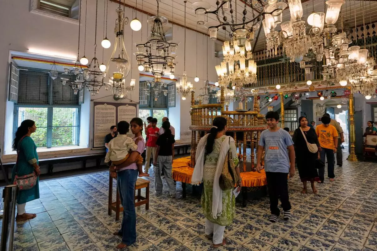 Tourists visit the main hall adorned with 19th-century Belgian crystal chandeliers and colorful glass lanterns at the 458-year-old Paradesi Synagogue in the historic Jew Town neighborhood of Kochi, India, Wednesday, May 20, 2026. (AP Photo/Aijaz Rahi)
