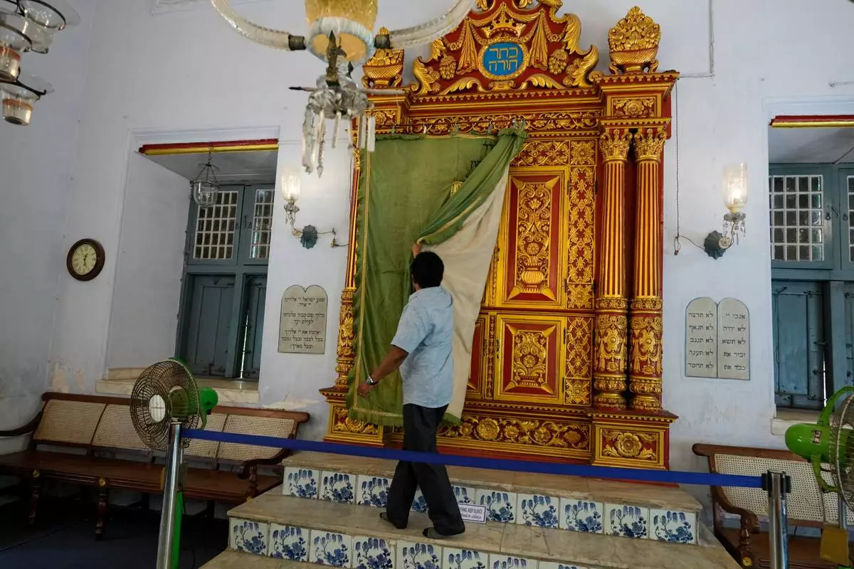 Synagogue trustee M.C. Praveen removes the ornate ceremonial curtain from the carved teakwood Torah ark, located on the western wall facing Jerusalem, at the 458-year-old Paradesi Synagogue in the historic Jew Town neighborhood of Kochi, India, Wednesday, May 20, 2026. (AP Photo/Aijaz Rahi)
