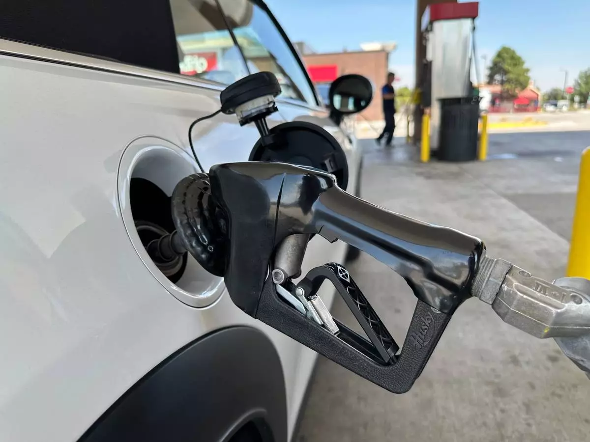A motorist fills up the fuel tank of a vehicle as another motorist follows suit in the background at a QT gasoline station Wednesday, Aug. 12, 2026, in Greenwood Village, Colo. (AP Photo/David Zalubowski)