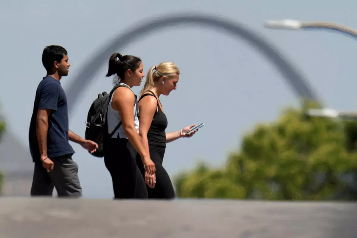 FILE - The Gateway Arch is seen through heatwaves in the distance as pedestrians use a crosswalk, July 23, 2025, in St. Louis. (AP Photo/Jeff Roberson, File)