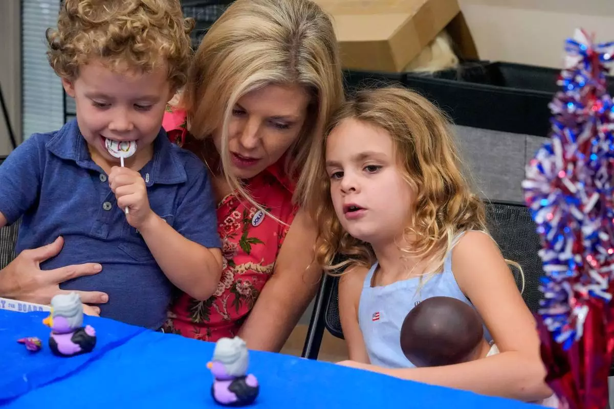Laura Jolly, center, wife of Florida Democratic gubernatorial candidate David Jolly, amuses their children Teddy, 5 and CeCe, 7, during a town hall meeting Saturday, Aug. 8, 2026, in Leesburg, Fla. (AP Photo/John Raoux)