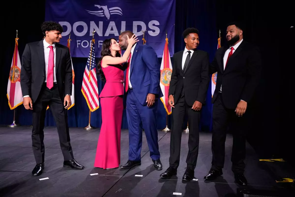 Florida Republican gubernatorial candidate Byron Donalds, center, is kissed by his wife Erika, while standing on stage with their children Darin, left, Damon, second from left, and Mason during at a primary election party Tuesday, Aug. 18, 2026, in Orlando, Fla. (AP Photo/John Raoux)