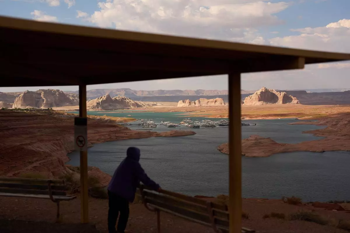 FILE - A person stands at an overlook near the Wahweap Marina on Lake Powell at the Glen Canyon National Recreation Area, July 15, 2026, near Page, Ariz. (AP Photo/John Locher, File)
