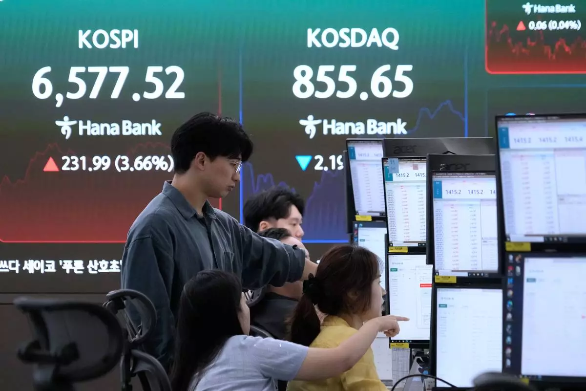 Currency traders watch monitors near a screen showing the Korea Composite Stock Price Index (KOSPI) at the foreign exchange dealing room of the Hana Bank headquarters in Seoul, South Korea, Wednesday, Aug. 12, 2026. (AP Photo/Ahn Young-joon)