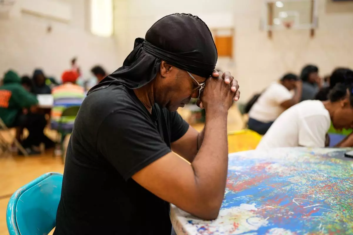 A person prays before receiving a free boxed lunch at City Life Center in Gary, Ind., Thursday, Aug. 20, 2026, more than a week after a deadly storm passed through the area. (AP Photo/Nam Y. Huh)