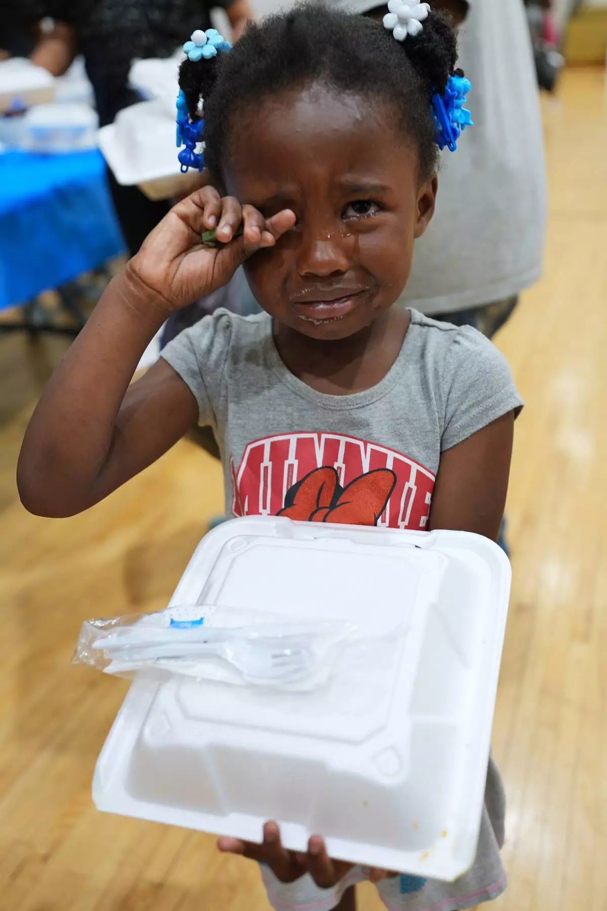 Tyanna Borom wipes her tears while holding a free boxed lunch at City Life Center in Gary, Ind., Thursday, Aug. 20, 2026, more than a week after a deadly storm passed through the area. (AP Photo/Nam Y. Huh)