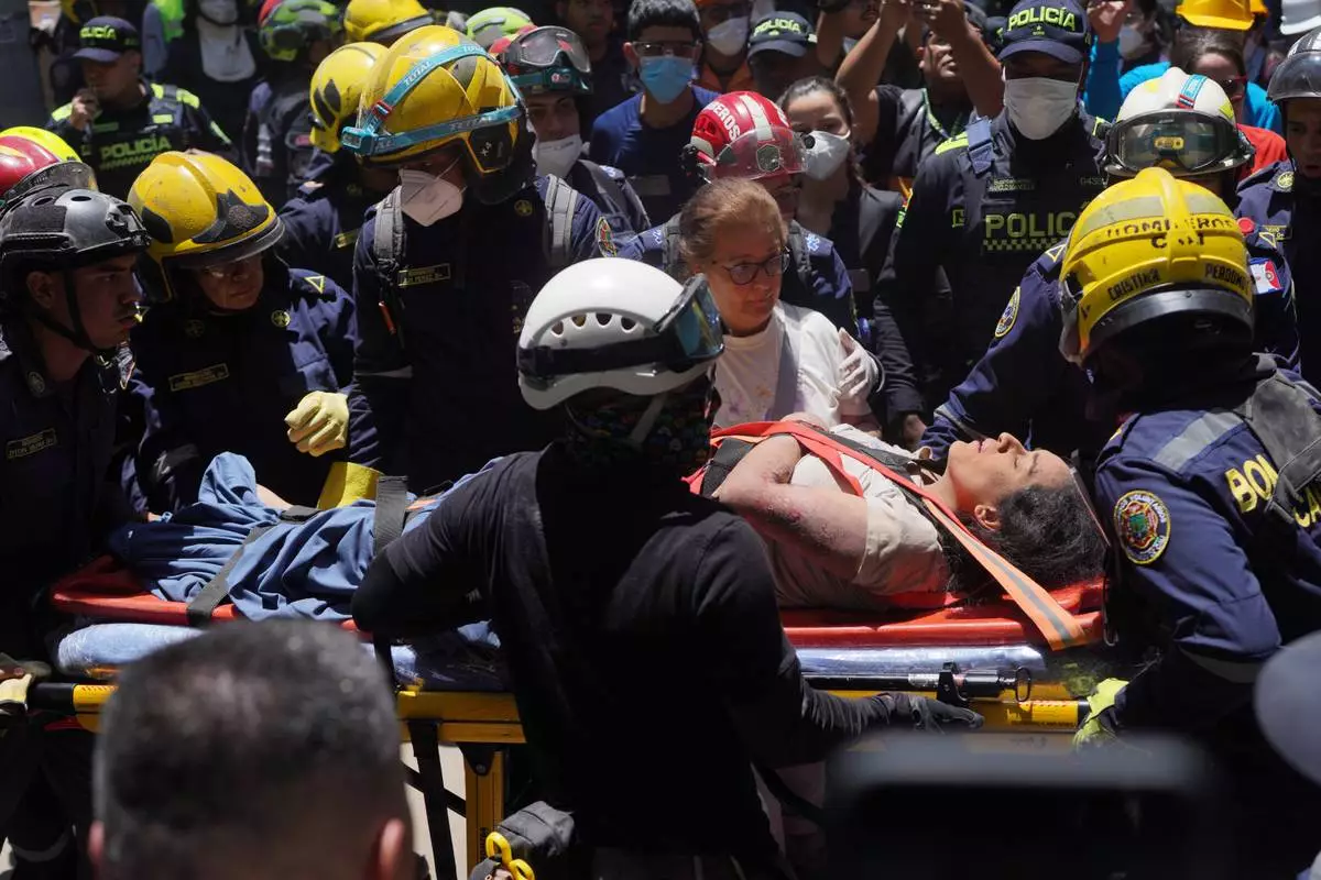 Rescue workers carry Diana Troncoso after pulling her from the rubble the day after an earthquake struck Cali, Colombia, Tuesday, Aug. 11, 2026. (AP Photo/Ivan Valencia) CORRECTION: Changes city to Cali, not Pereira.