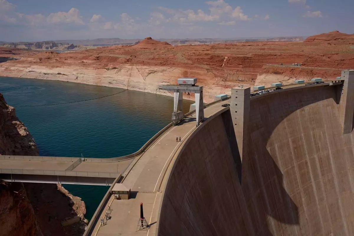 People walk across the Glen Canyon Dam near Lake Powell at the Glen Canyon National Recreation Area, Tuesday, July 14, 2026, near Page, Nev. (AP Photo/John Locher)