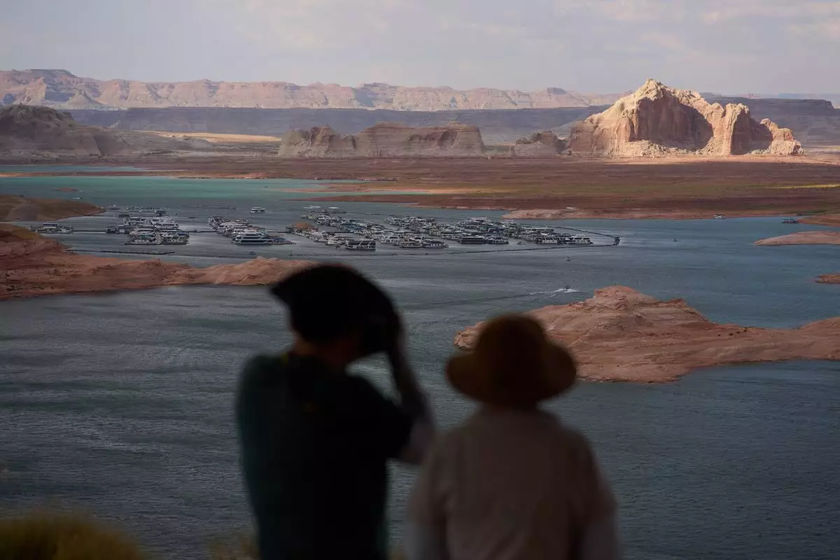 People stand on a lookout on Lake Powell at the Glen Canyon National Recreation Area, Tuesday, July 14, 2026, near Page, Nev. (AP Photo/John Locher)