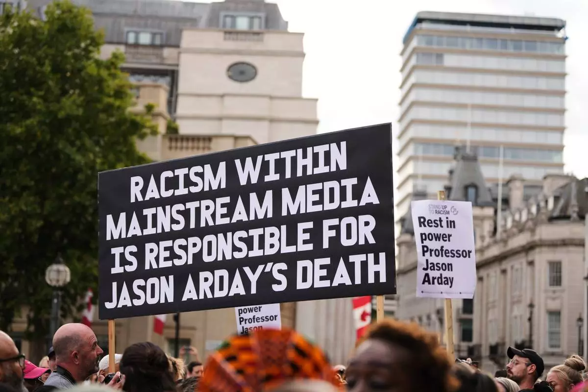 People hold signs during a vigil held by Stand Up to Racism in memory of late University of Cambridge professor Jason Arday at Trafalgar Square in London, Monday, Aug. 17, 2026. (AP Photo/Kirsty Wigglesworth)