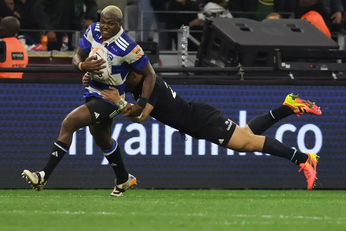 Stormers' Hacjivah Dayimani, left, is tackled by All Blacks' Caleb Clarke during a friendly rugby match between Stormers and All Blacks, in Cape Town, South Africa, Friday, Aug. 7, 2026. (AP Photo/Halden Krog)