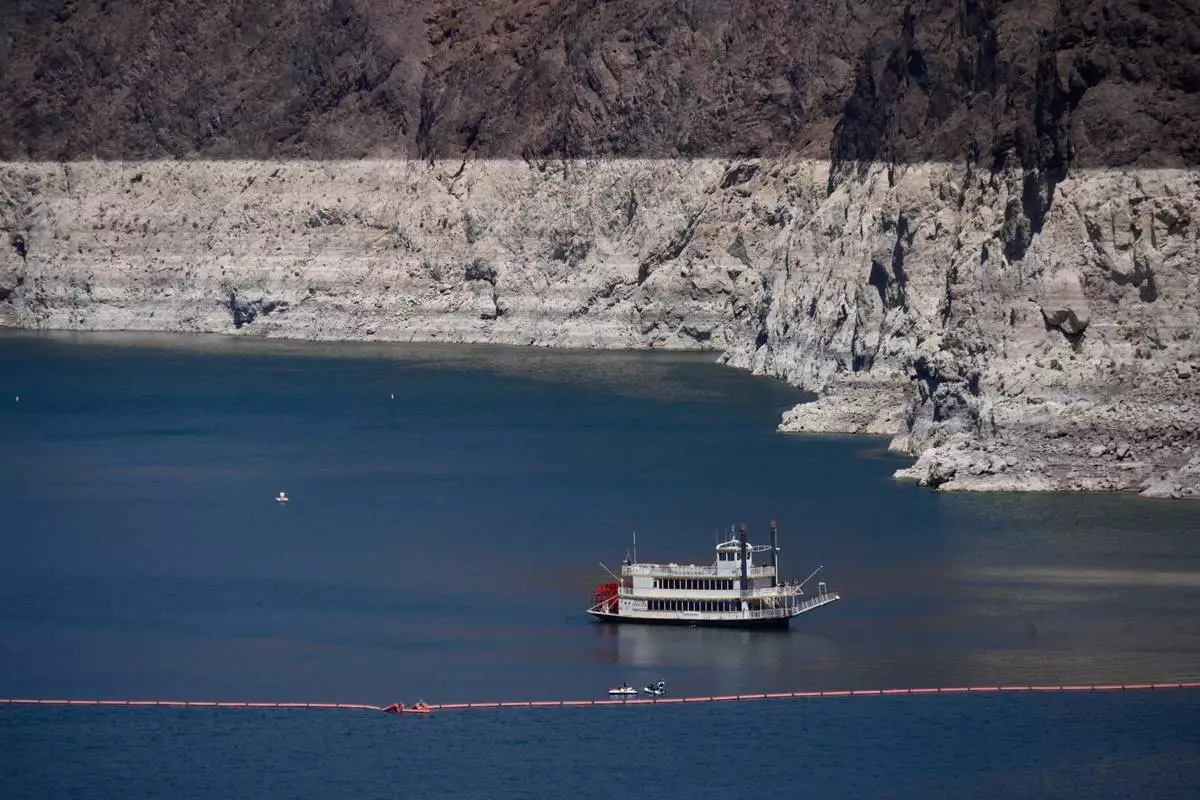 A paddle boat in Lake Mead near the Hoover Dam, far below the bathtub ring of light minerals indicating the lack of water, near Boulder City, Nev., on Friday, Aug. 7, 2026. (AP Photo/Ty ONeil)
