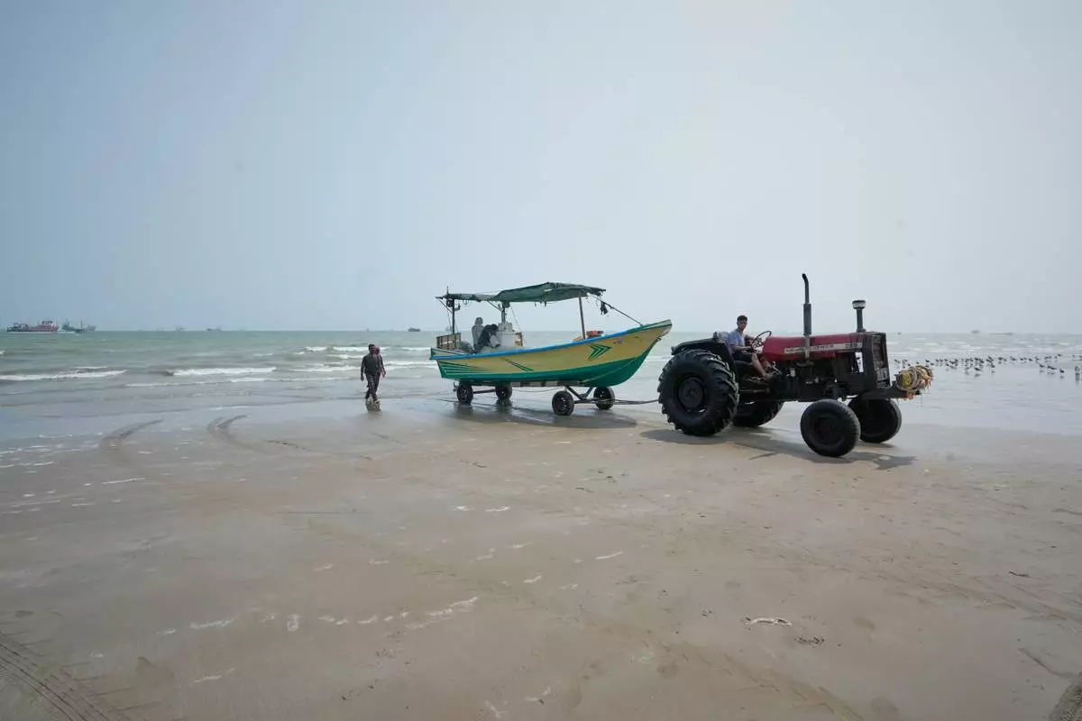 A tractor pulls a motorboat from the water onto the beach as commercial vessels lie anchored in the Strait of Hormuz off Bandar Abbas, Iran, Monday, Sept. 7, 2026. (AP Photo/Vahid Salemi)