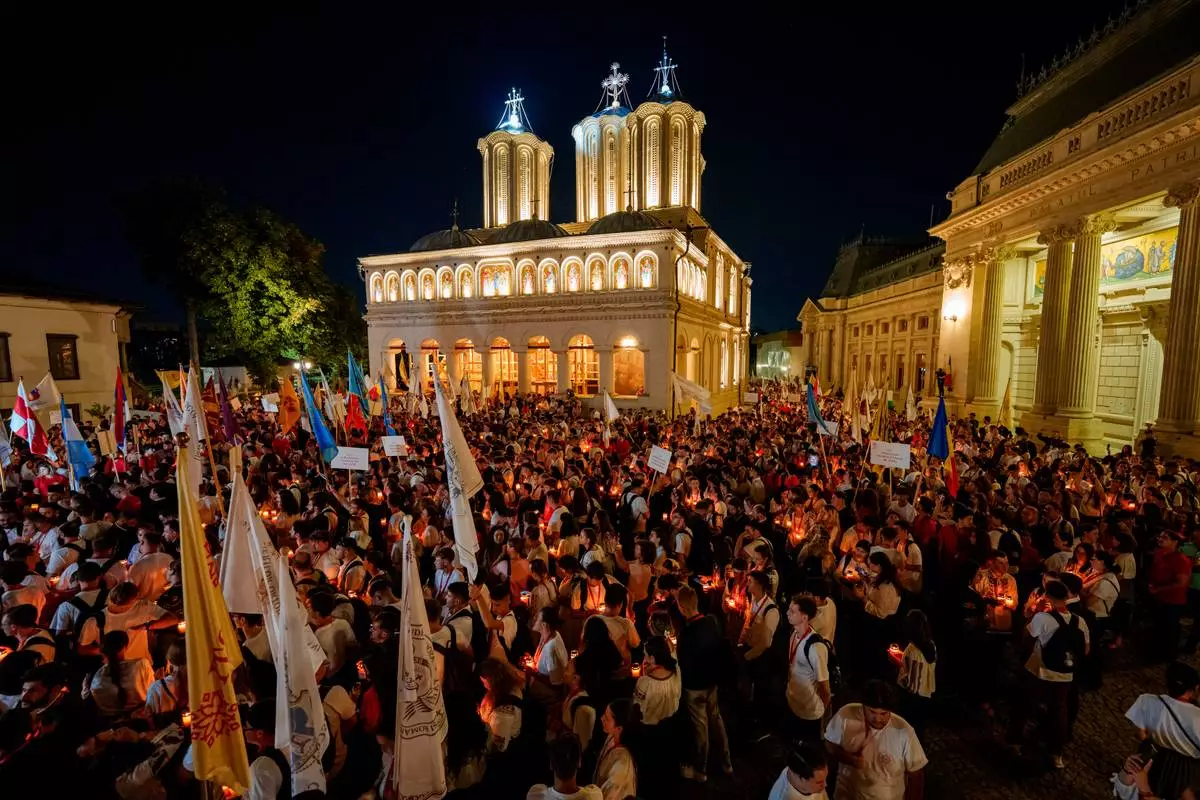 People hold candles standing outside the Patriarchal Cathedral at the end of the Procession of Lights, part of a four-day program of the International Meeting of Orthodox Youth (ITO), in Bucharest, Romania, Wednesday, Sept. 2, 2026. (AP Photo/Andreea Alexandru)