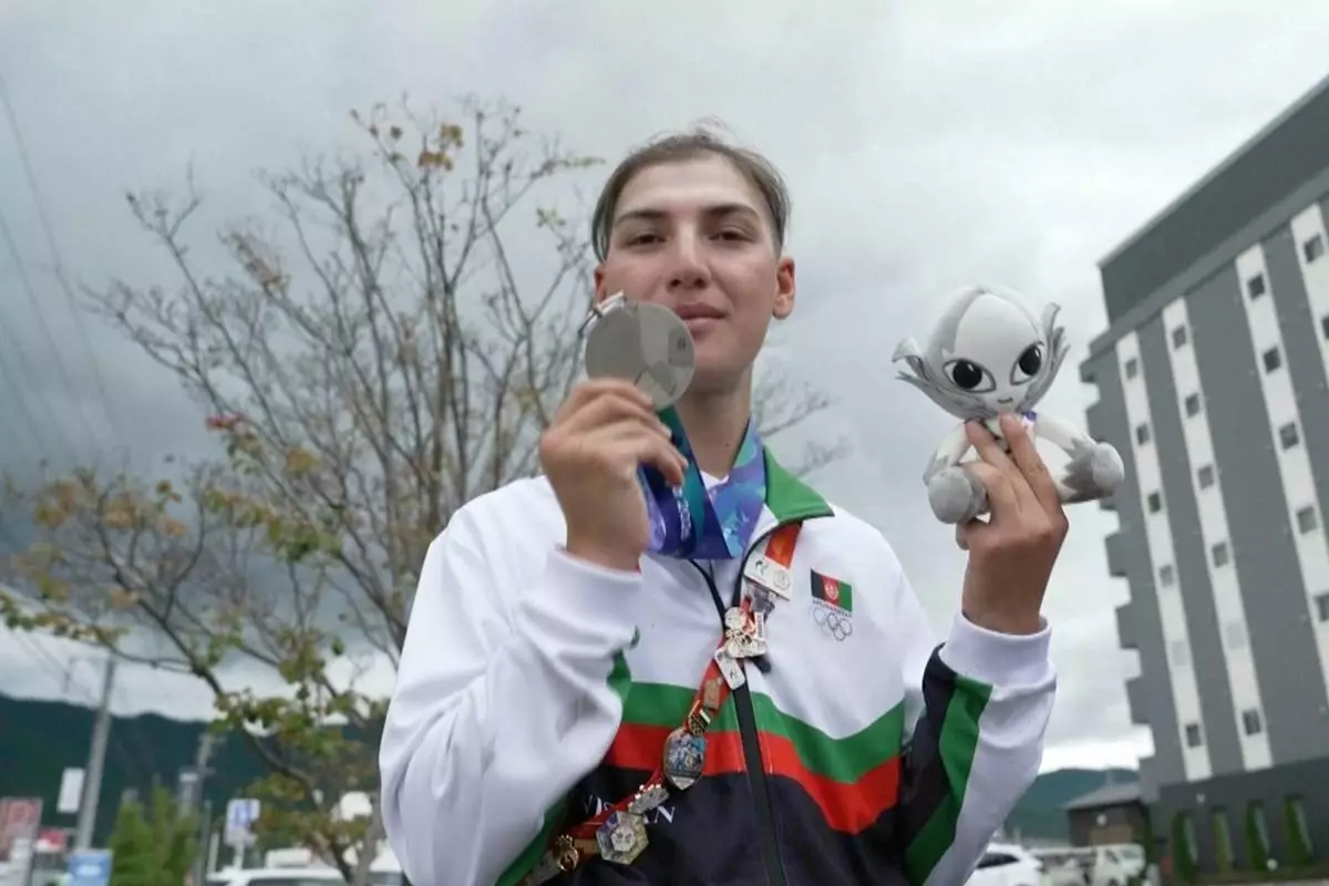 In this image made from video, Afghanistan's Fariba Hashim displays the silver medal she won for Women's Road Race, in Shinshiro, Japan, Wednesday, Sept. 23, 2026. (SNTV via AP)