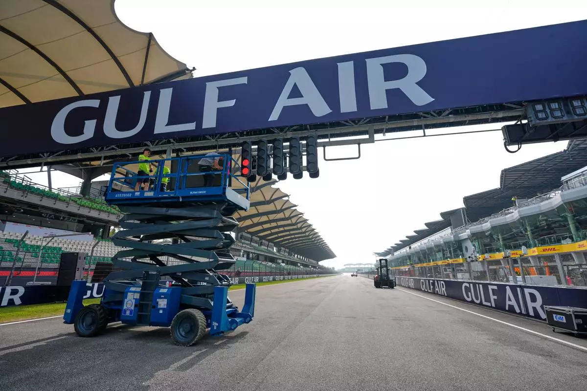 Workers use a scissor lift to install a banner over the track ahead of the Bahrain Grand Prix in Malaysia at the Sepang International Circuit in Sepang, Malaysia, Wednesday, Sept. 30, 2026. (AP Photo/Vincent Thian)
