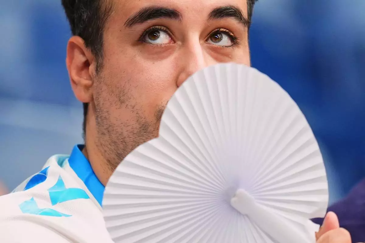 FILE - A man uses a fan to cool off during the La Liga soccer match between Real Madrid and Malaga at the Bernabeu stadium in Madrid, Spain, Aug. 30, 2026. (AP Photo/Manu Fernandez, File)