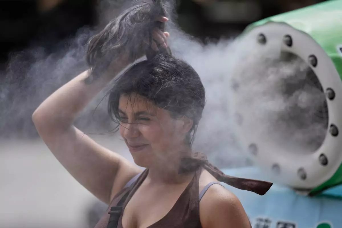 FILE - A person cools off at a cooling mist spot on a hot and sunny day at the Sensoji Buddhist temple in Tokyo's Asakusa district on Aug. 7, 2026. (AP Photo/Eugene Hoshiko, File)