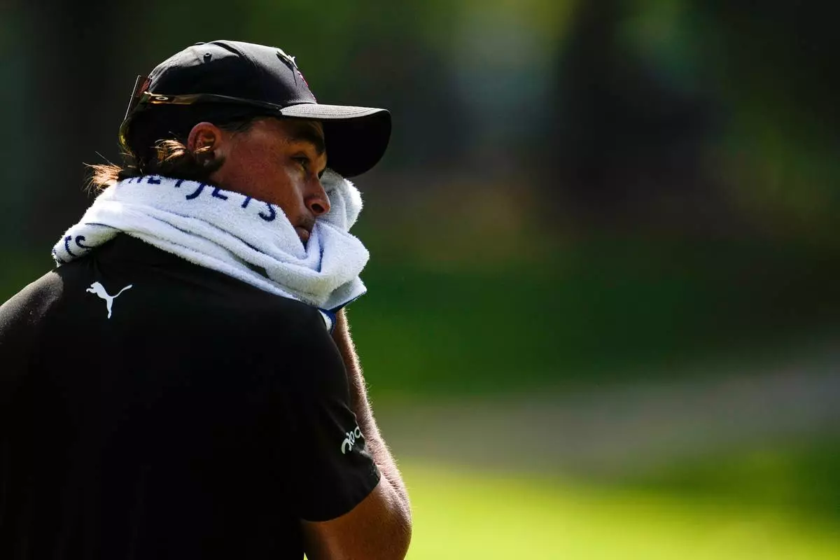 FILE - Rickie Fowler wipes his face in the heat off the fifth tee box during the first round of the St. Jude Championship golf tournament Aug. 13, 2026, in Memphis, Tenn. (AP Photo/George Walker IV, File)