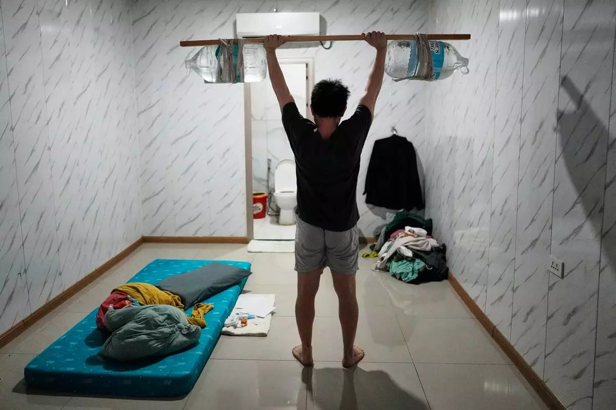 A rescued Vietnamese scam worker shows how he exercises using improvised weights made of a wooden stick and water jugs as he waits to be repatriated at the Presidential Anti-Organized Crime Commission temporary detention center, a former scam compound in Pasay, Philippines, Tuesday, June 3, 2025. (AP Photo/Aaron Favila)