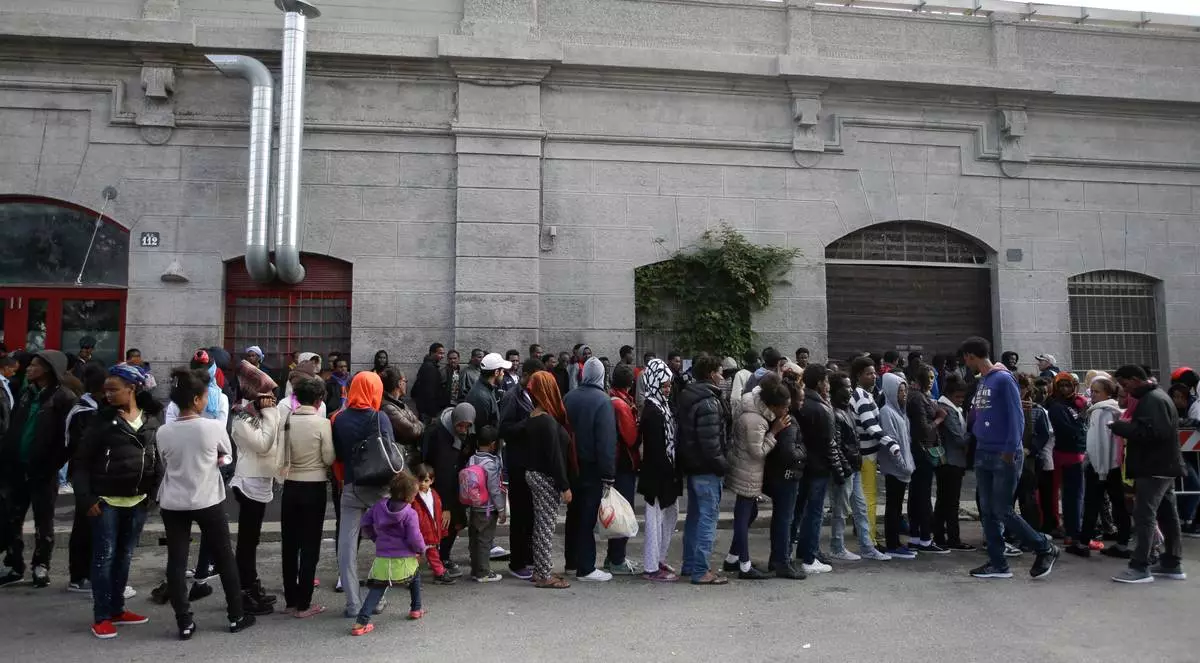 FILE - Migrants queue to enter a refectory in Milan, Italy, on Oct. 21, 2016. (AP Photo/Luca Bruno, File)