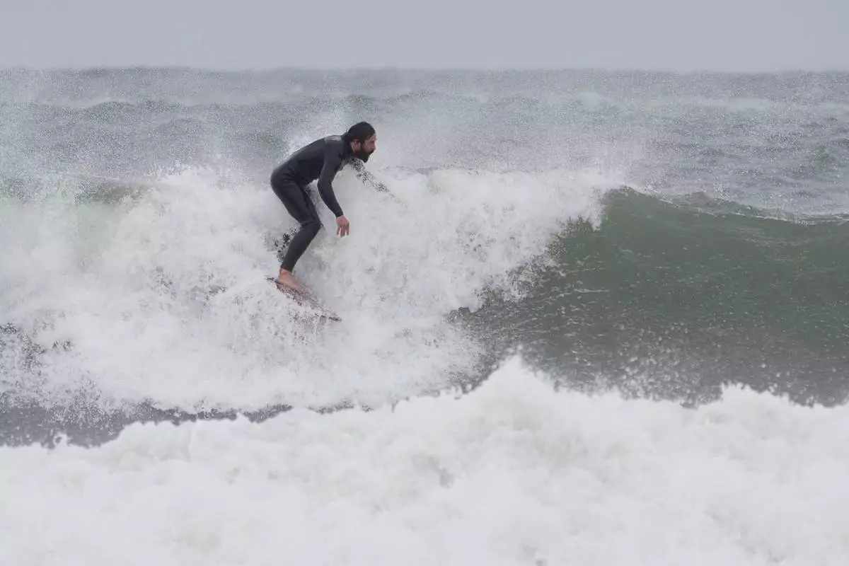 A surfer rides a wave during a nor'easter storm, Friday, Sept. 25, 2026, in Gloucester, Mass.(AP Photo/Robert F. Bukaty)