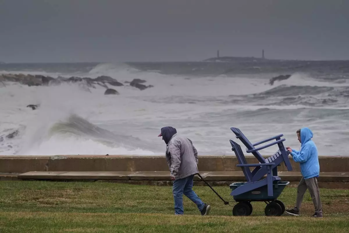 Chuck and Teresa Palmieri move lawn furniture to a safe location at a relative's seaside property as the Atlantic Ocean kicks up surf during the early stages of a nor'easter storm, Friday, Sept. 25, 2026, in Gloucester, Mass. (AP Photo/Robert F. Bukaty)