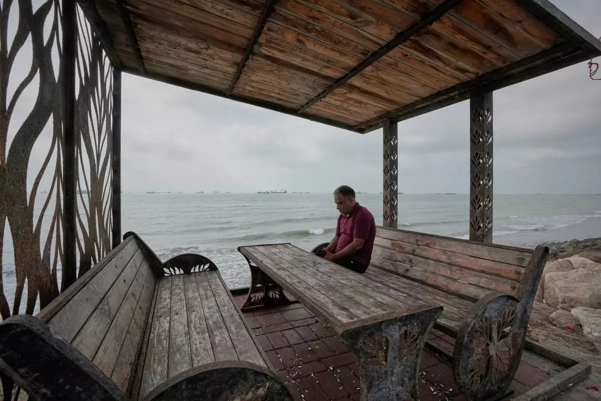 A man rests at a waterfront shelter as commercial vessels lie anchored in the Strait of Hormuz off Bandar Abbas, Iran, Friday, Sept. 4, 2026. (AP Photo/Vahid Salemi)