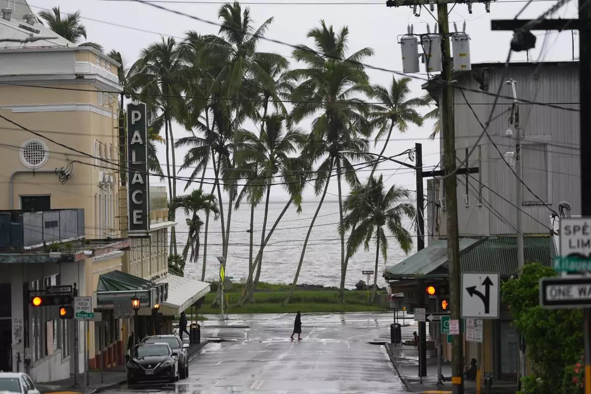 A man crosses the road as Hurricane Nolo sits nearby Saturday, Sept. 26, 2026, in Hilo, Hawaii. (AP Photo/Gregory Bull)