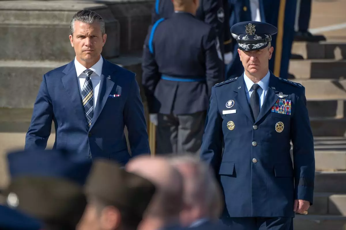 Defense Secretary Pete Hegseth, left, and Chairman of the Joint Chiefs of Staff Gen. Dan Caine, right, arrive for the POW/MIA National Recognition Day Ceremony at the Pentagon, Friday, Sept. 18, 2026, in Washington. (AP Photo/Mark Schiefelbein)