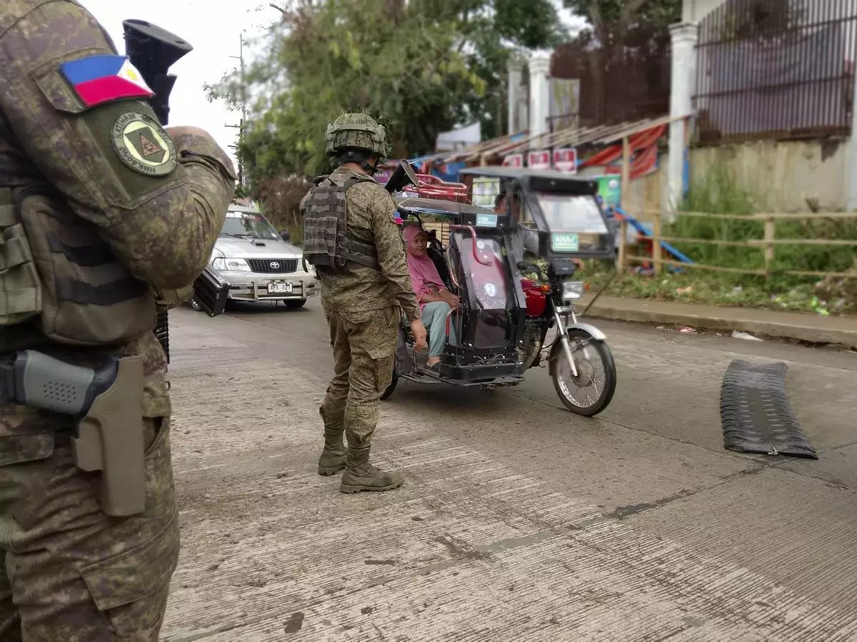 In this photo taken with a smartphone, Army soldiers check the flow of vehical traffic along the highway in Marantao town, Lanao del Sur province, southern Philippines on Sunday Sept 13, 2026. (AP Photo/ Froilan Gallardo)