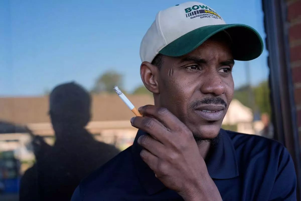 Samba Diallo, a Mauritanian immigrant, pauses for a cigarette at a convenience store and gas station after his regular appointment at an Immigration and Customs Enforcement office in Cincinnati, Monday, Sept. 14, 2026. (AP Photo/Carolyn Kaster)