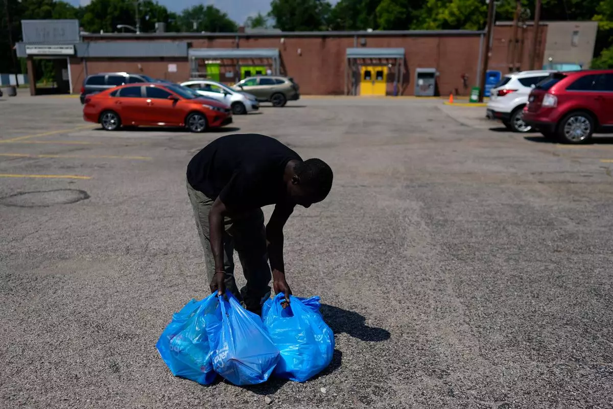 Harounat Sarre, a Mauritanian immigrant, rearranges his groceries in the parking lot of Valley Interfaith Community Resource Center as he walks to his shared apartment in Lockland, Ohio, Friday, July 31, 2026. (AP Photo/Carolyn Kaster)