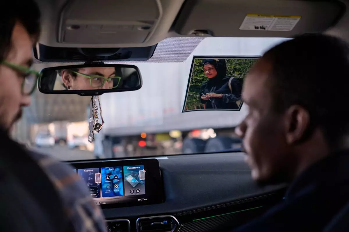 A photo of Samba Diallo's wife hangs from the inside of his car as he's driven home by Vincent Wilson, left, following an Immigration and Customs Enforcement appointment in Cincinnati, Monday, Sept. 14, 2026. Diallo posts the picture of his wife, who still lives in their native Mauritania, on the inside of his windshield to see her whenever he drives. (AP Photo Carolyn Kaster)