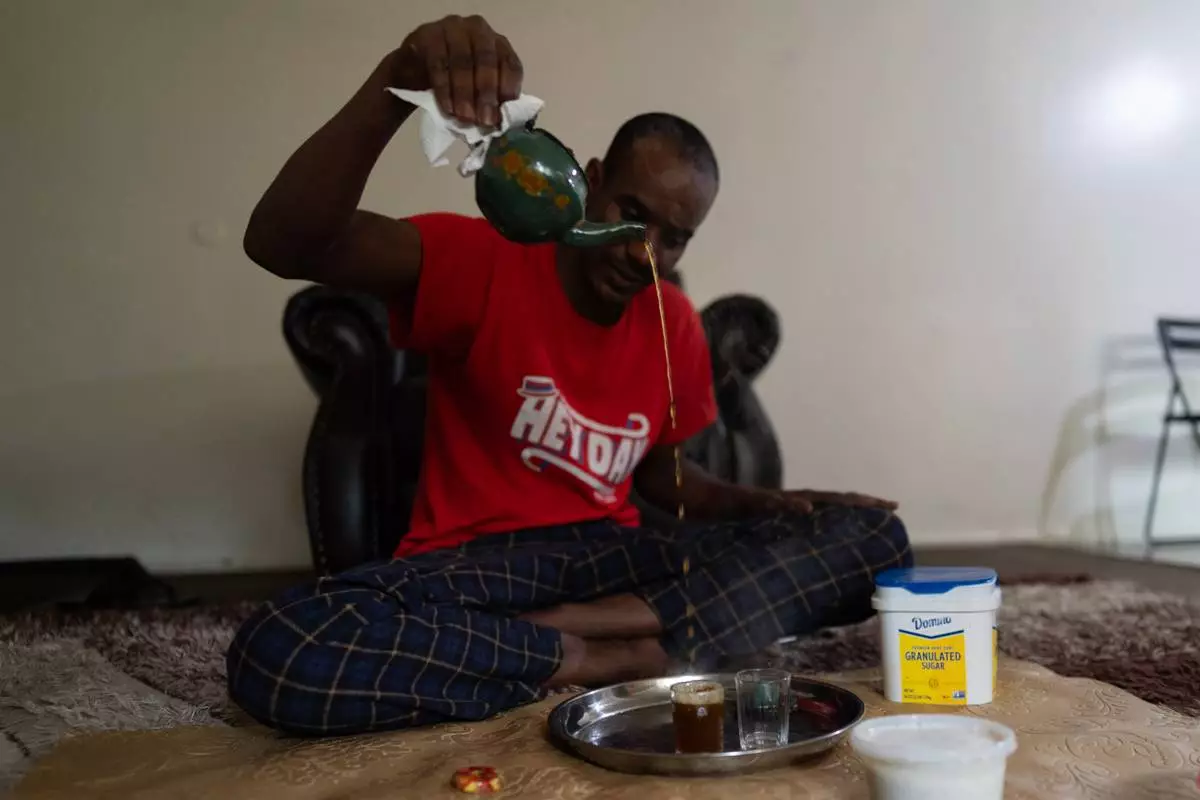 Samba Diallo, a Mauritanian immigrant, makes traditional green tea on the living room floor of his shared apartment in Lockland, Ohio, Friday, July 17, 2026. (AP Photo/Carolyn Kaster)