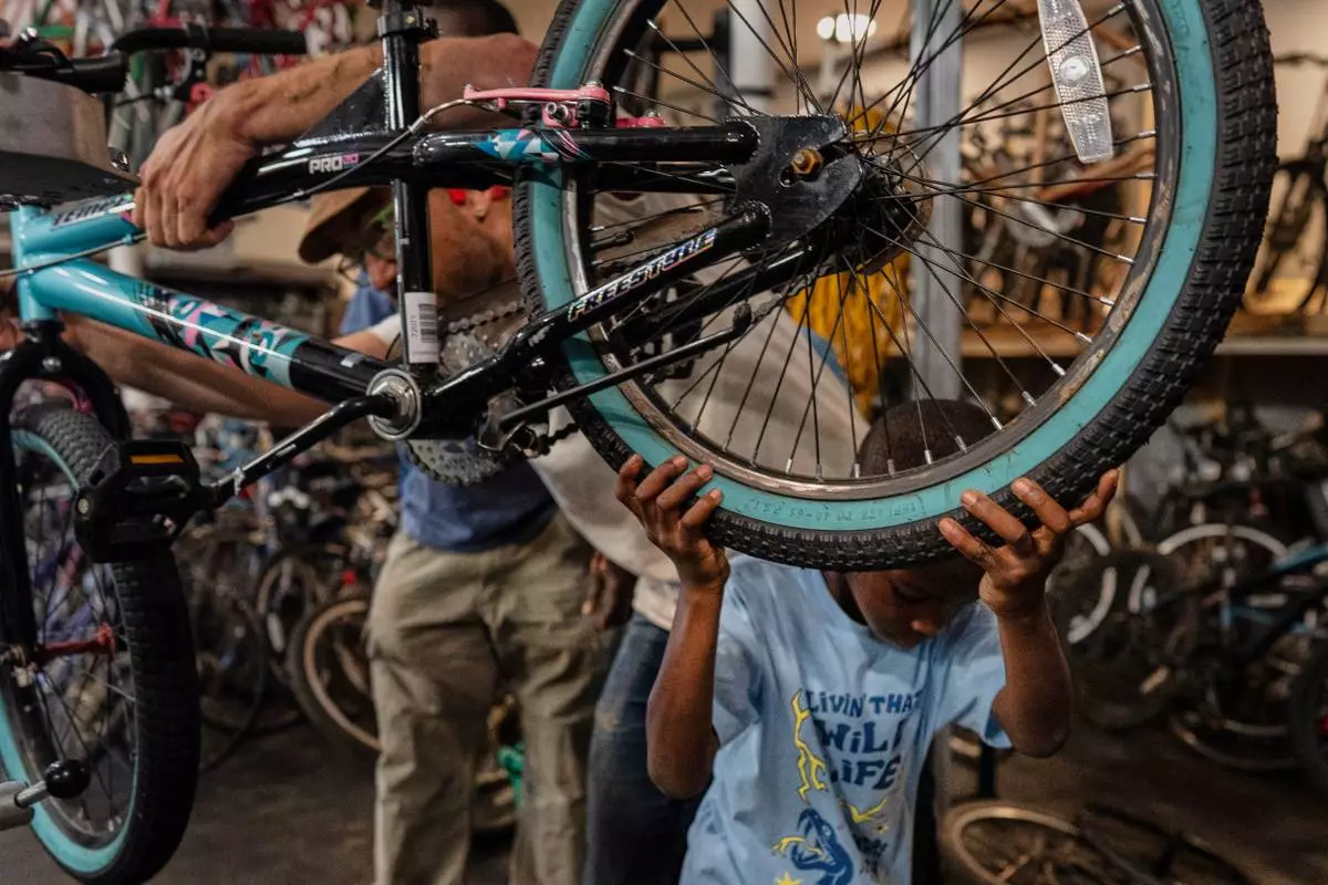 Vincent Wilson, left, who takes in donated, broken bikes and offers them up in the community to anyone who helps fix them up, repairs a bike with the help a seven-year-old boy at Bikes and Stuff in Lockland, Ohio, Friday, July 10, 2026. (AP Photo/Carolyn Kaster)