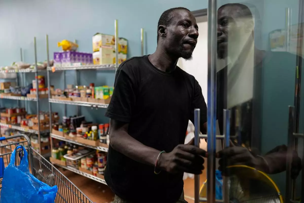 Harounat Sarre, a Mauritanian immigrant, opens a cooler as he gets groceries from Valley Interfaith Community Resource Center in Lockland, Ohio, Friday, July 31, 2026. (AP Photo/Carolyn Kaster)