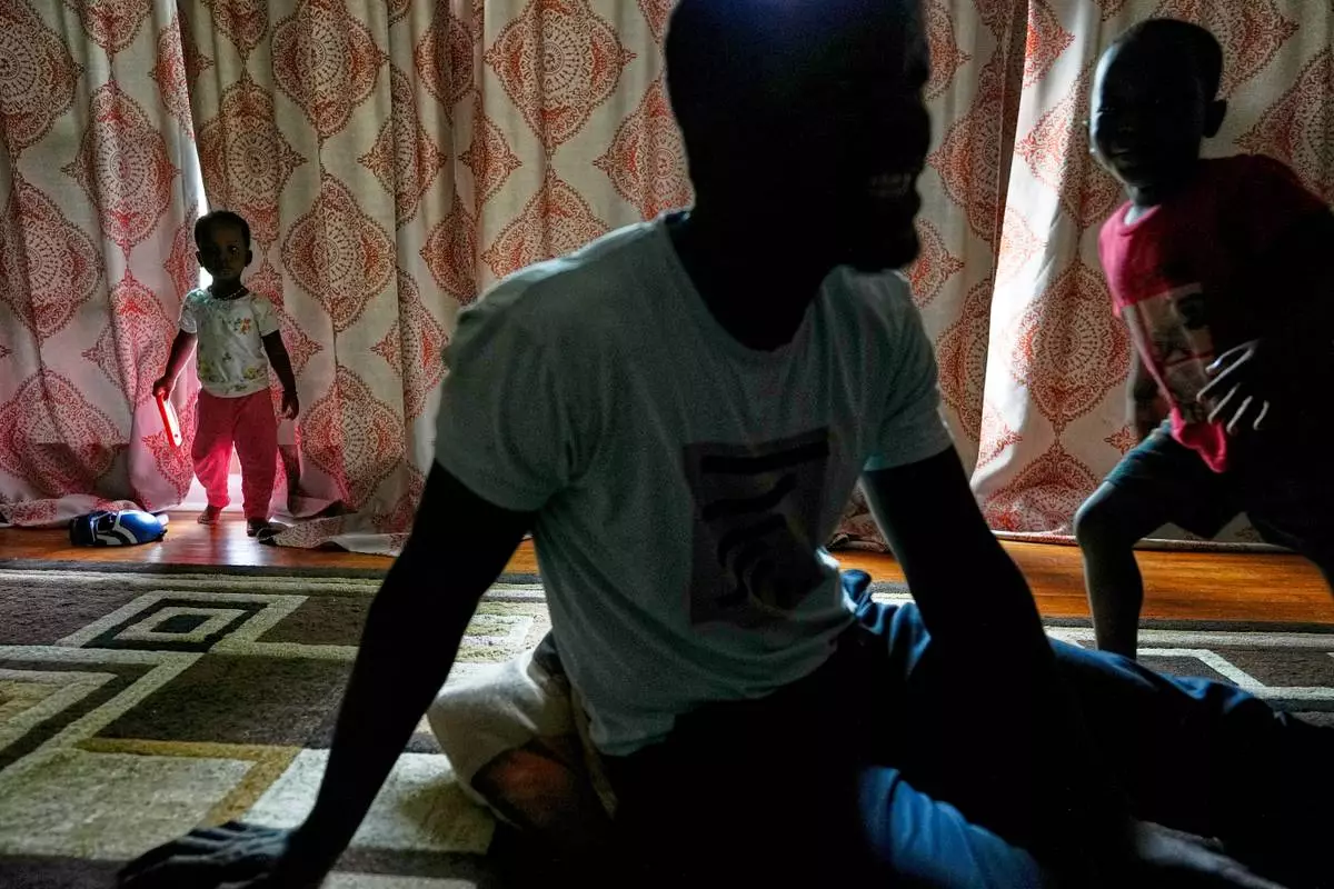 Khalidou Sy, a Mauritanian immigrant, sits with his children in the family's home in Lockland, Ohio, Friday, July 31, 2026. Sy, a well-known hip-hop artist back home, had been jailed for his music critical of the country's repressive government. (AP Photo/Carolyn Kaster)
