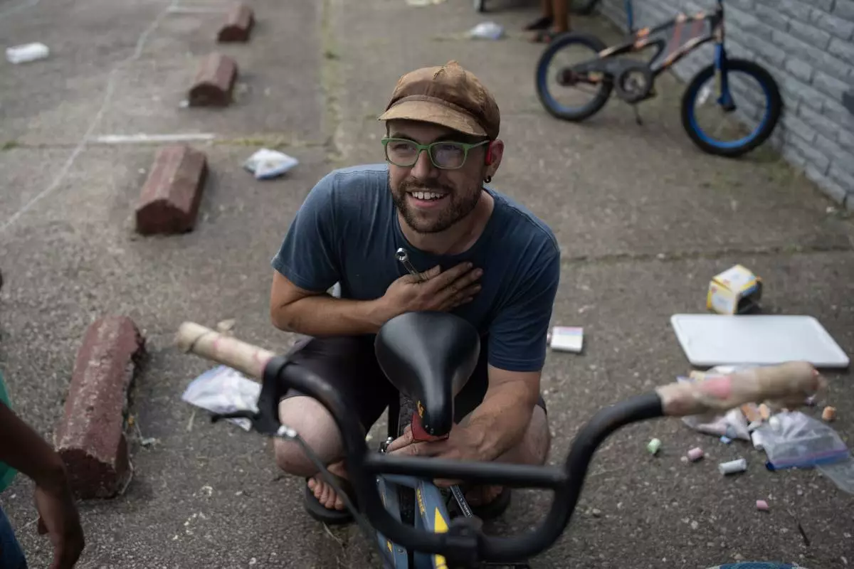 Vincent Wilson, who takes in donated, broken bikes and offers them up to the community for anyone who helps fix them up, looks up as he fixes a bike in front of Bikes and Stuff in Lockland, Ohio, Friday, July 17, 2026. (AP Photo/Carolyn Kaster)