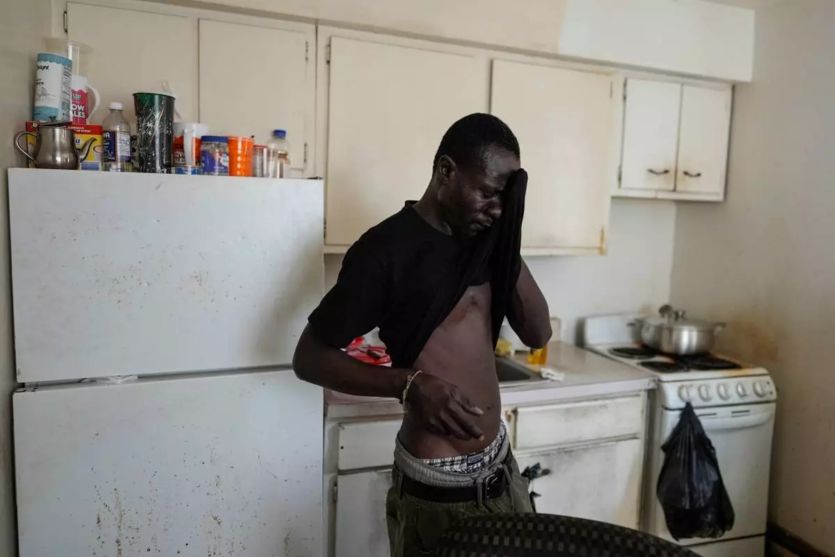 Harounat Sarre, a Mauritanian immigrant, wipes away sweat after unpacking groceries from a food pantry into the refrigerator of his shared apartment in Lockland, Ohio, Friday, July 31, 2026. (AP Photo/Carolyn Kaster)