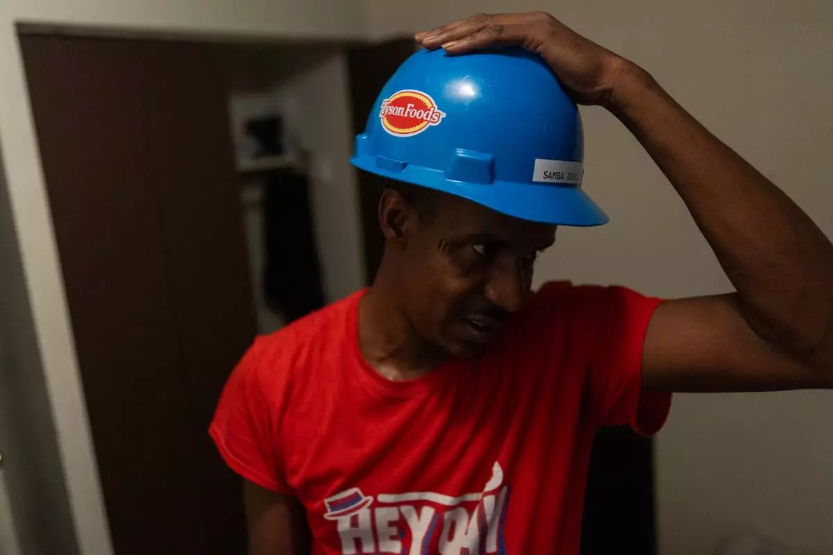 Samba Diallo, a Mauritanian immigrant, tries on a work safety helmet in a bedroom of his shared apartment in Lockland, Ohio, Friday, July 17, 2026. Diallo, like many from Mauritania, had fled a country where he was persecuted for opposing the country’s repressive government. (AP Photo/Carolyn Kaster)